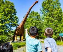 two kids looking up at a dinosaur