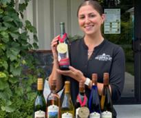 a woman holding up a bottle of wine with a medal