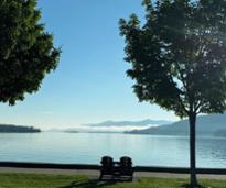Image of Lake George with two chairs and trees by the shoreline