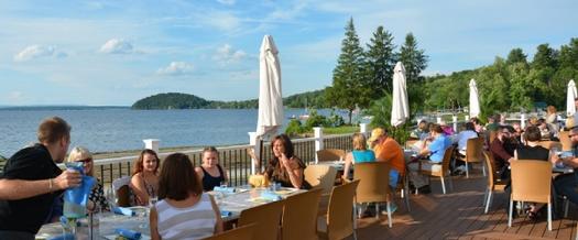 people dining on a patio near a lake