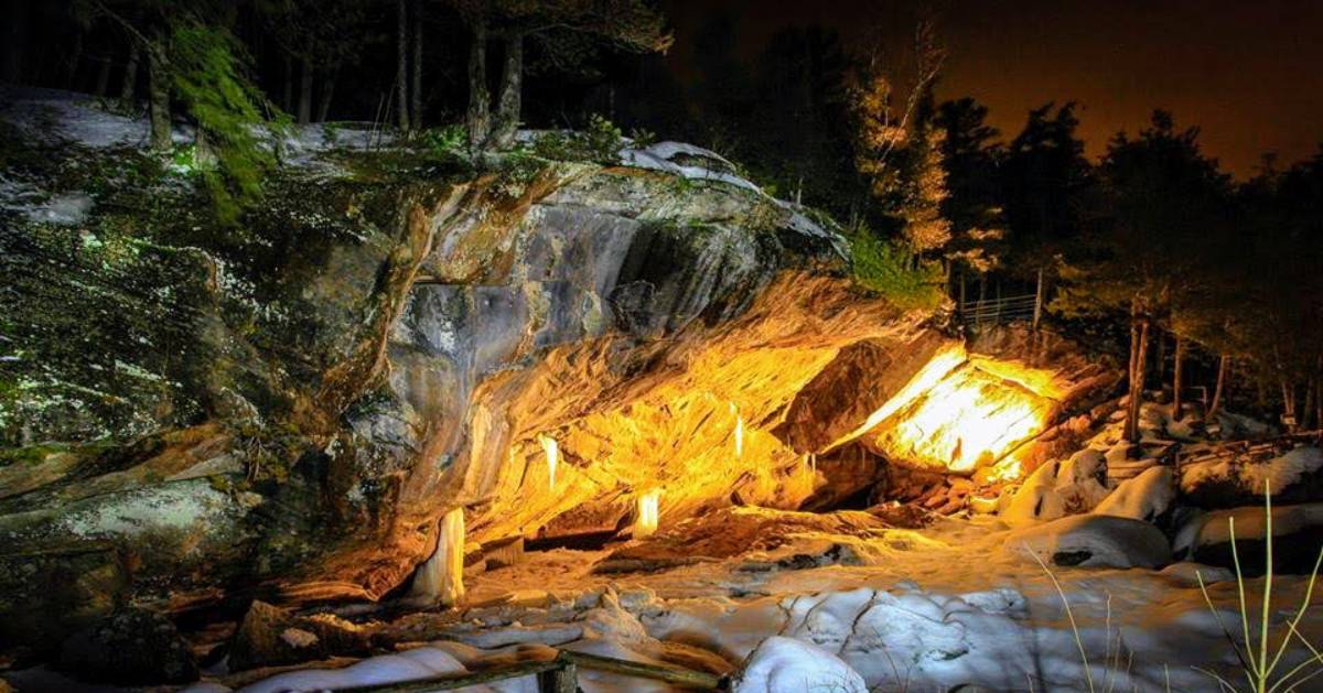 a cave entrance at night with yellow lights shining on it