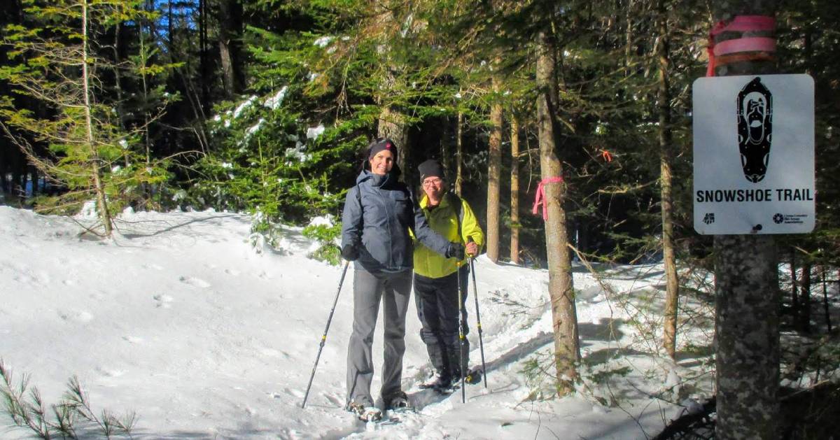 two women near snowshoe trail sign