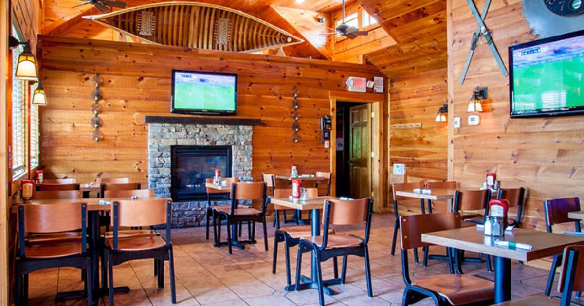 a stone fireplace in the back of a dining room with tables and chairs