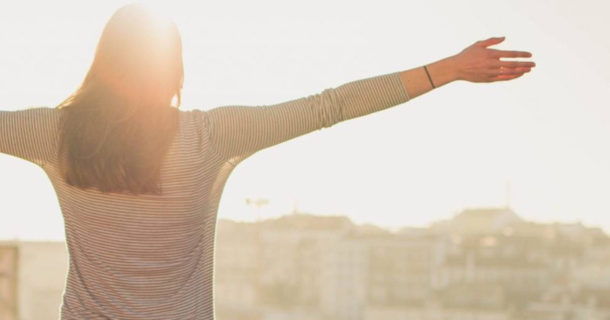 woman with her back to the camera reaching her arms up triumphantly