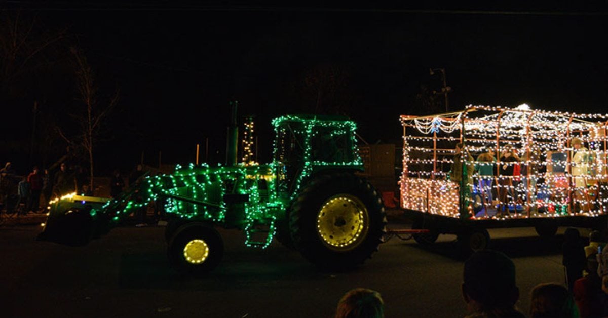 green tractor decorated with holiday lights in a parade