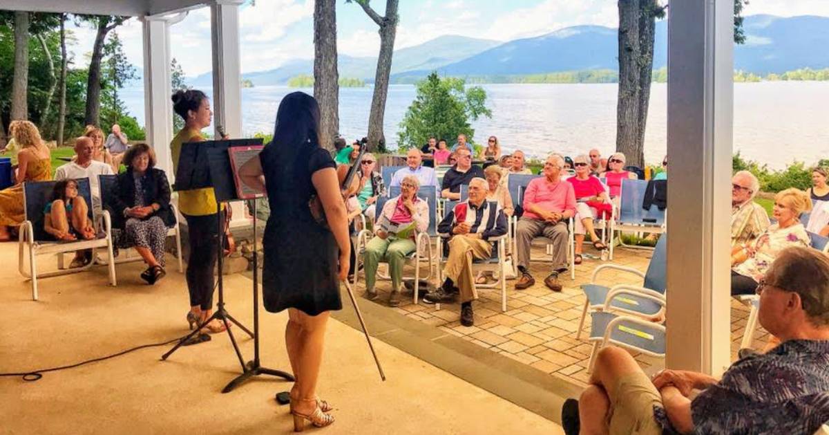 musicians about to perform in front of a crowd by the lake