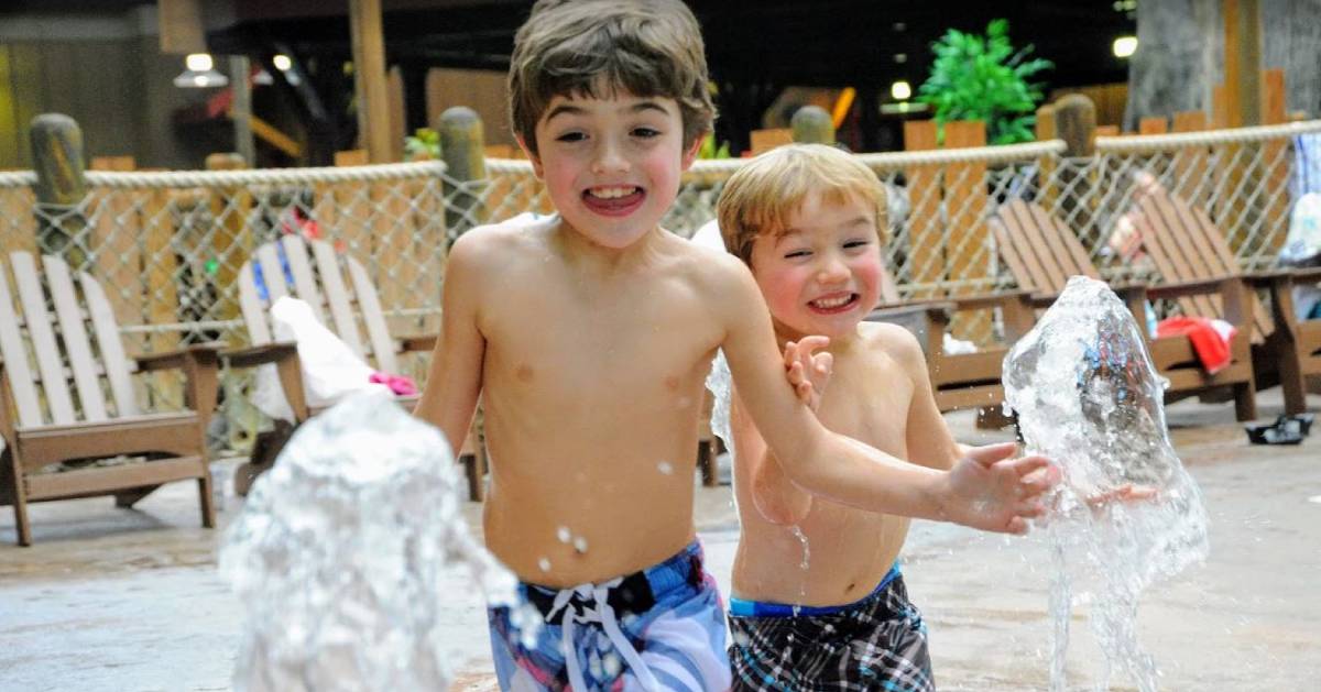 two little boys smiling and playing in an indoor water park