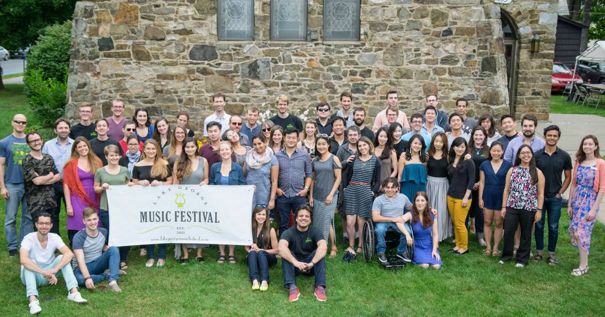 music festival group posing together with sign