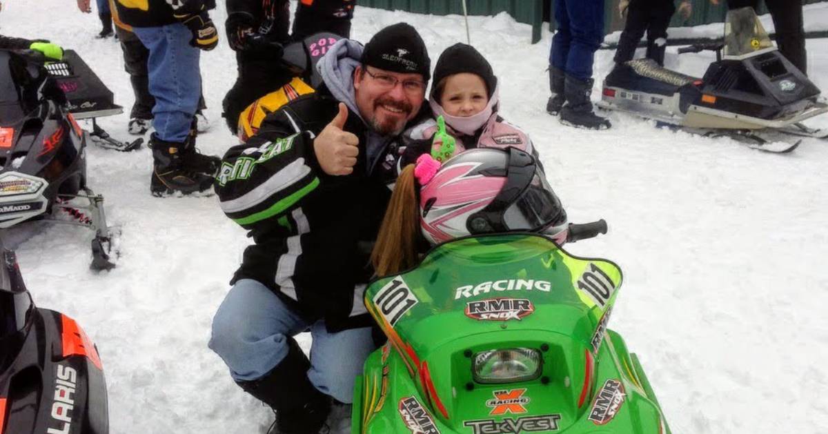 man with kid in snowmobile