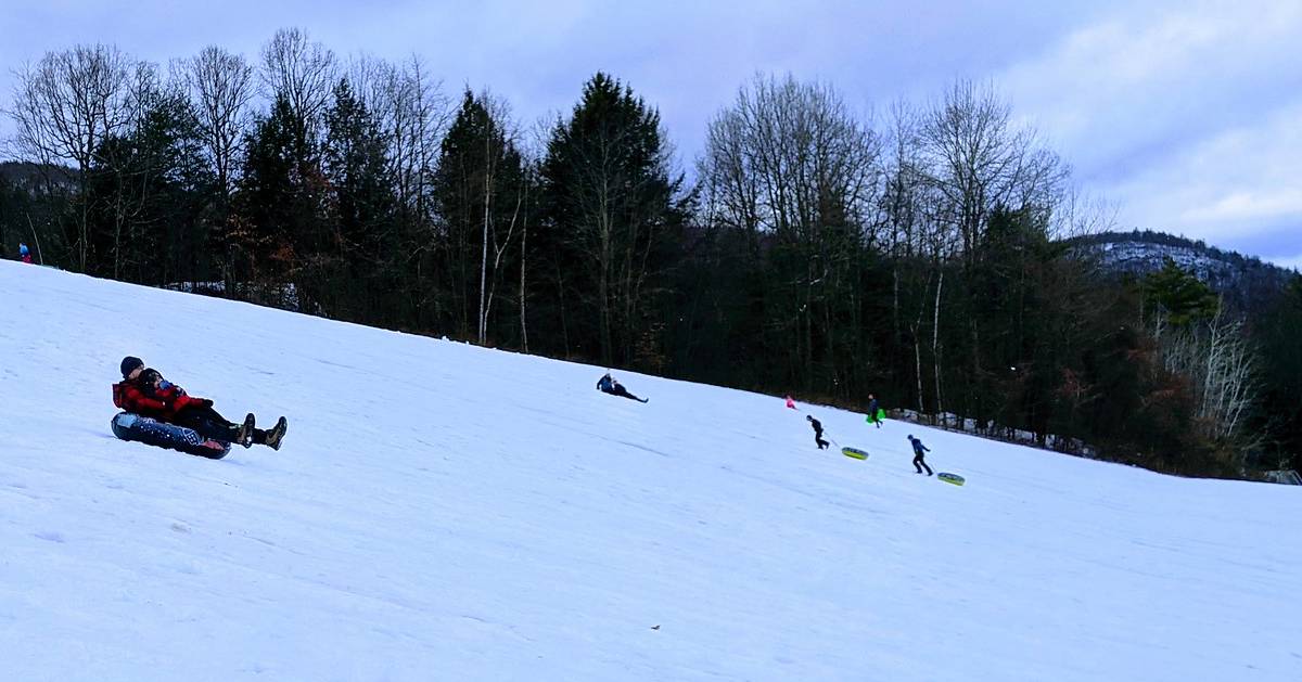 people going down a snow tubing hill