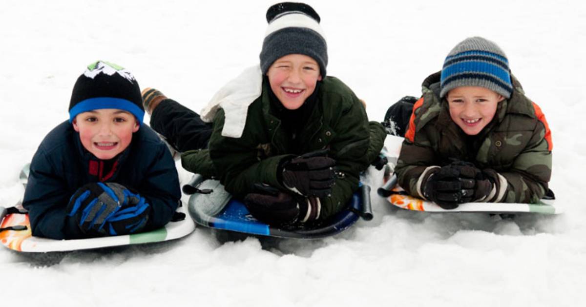 three boys on sleds in winter