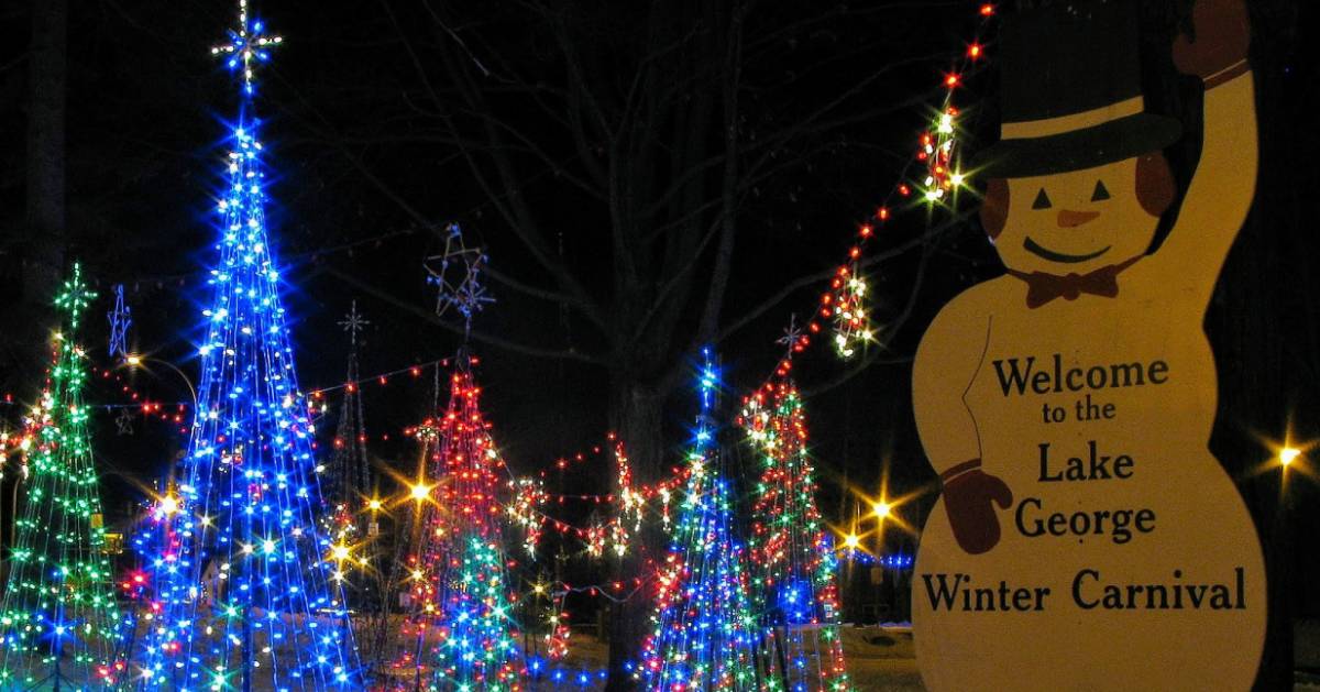 lit up fake trees by Lake George Winter Carnival sign