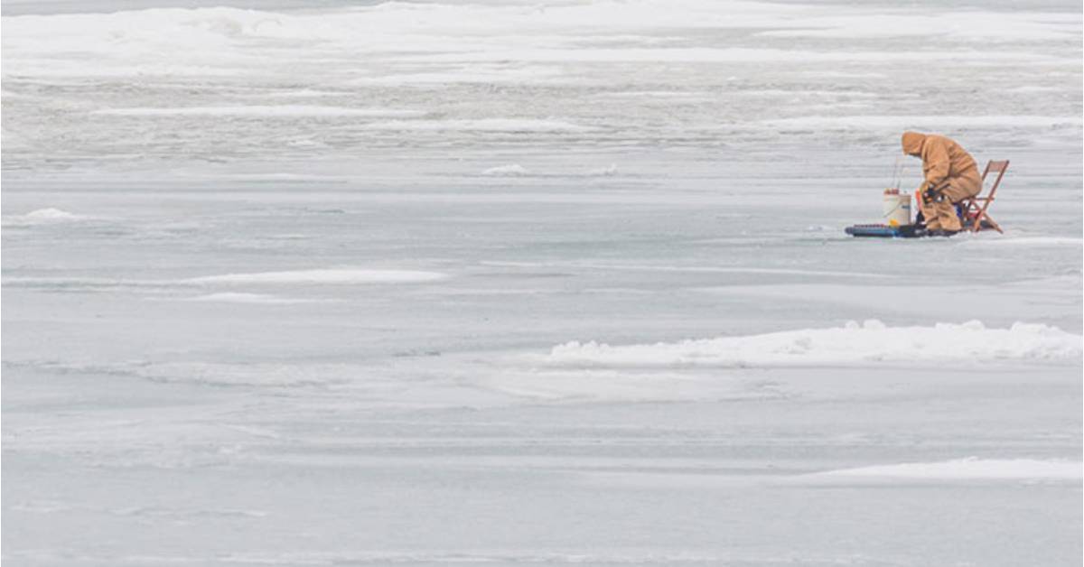 person on frozen lake ice fishing