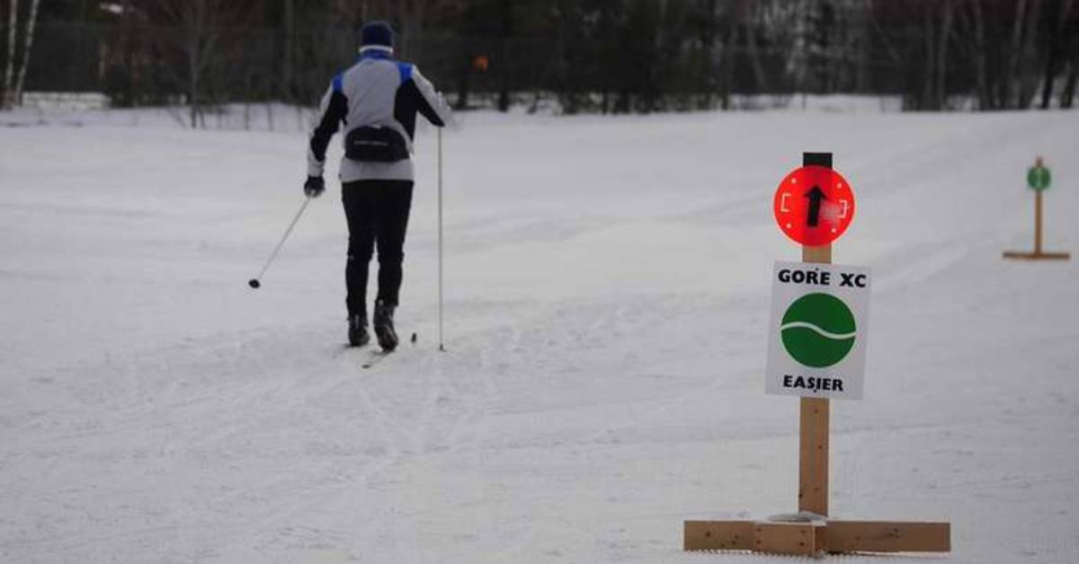 man cross country skiing with sign near a trail