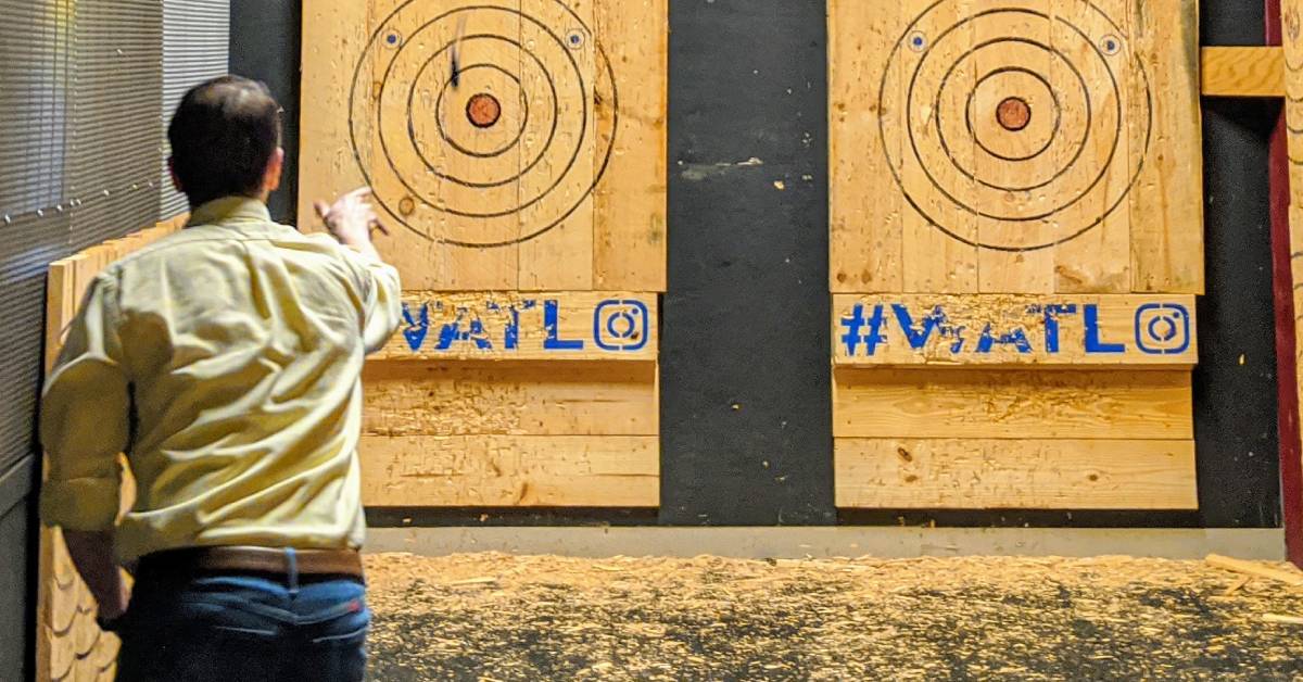 man throwing axe at a wooden target with a bullseye on a wall