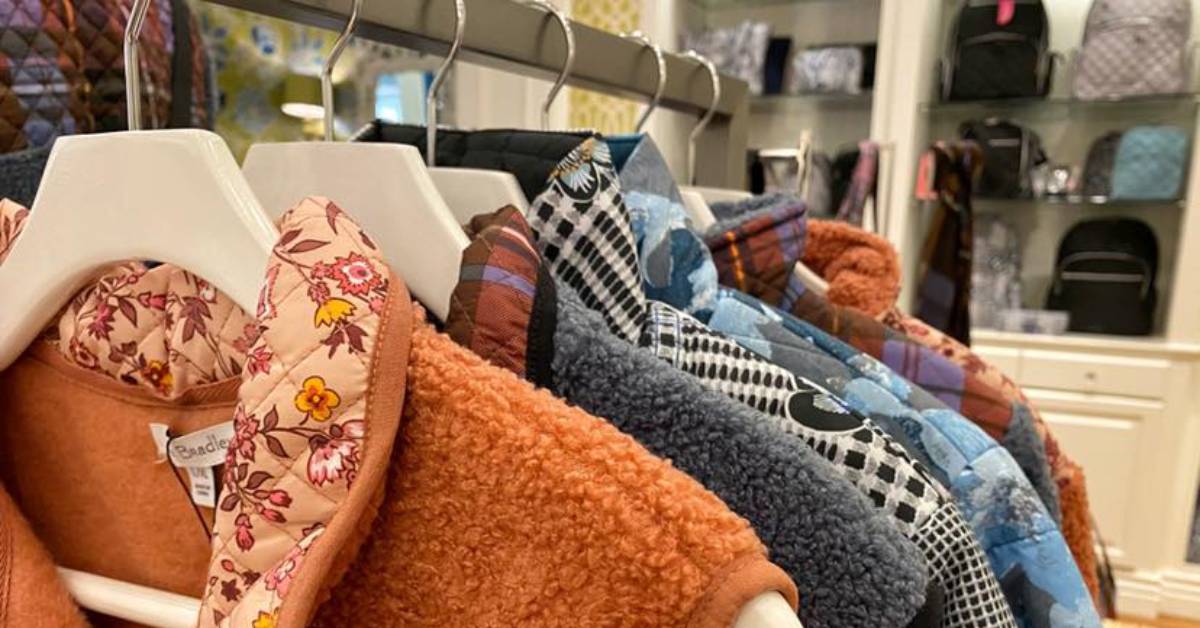 fuzzy vests and coats on a clothing rack in a store