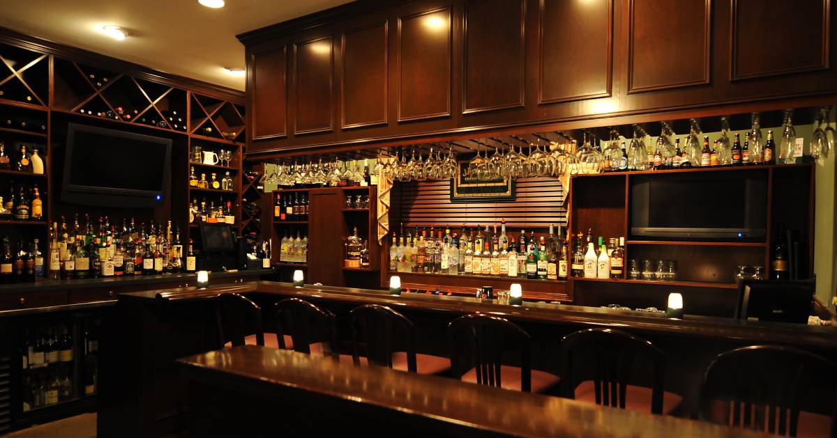 bar area with wooden chairs and bottles in the back