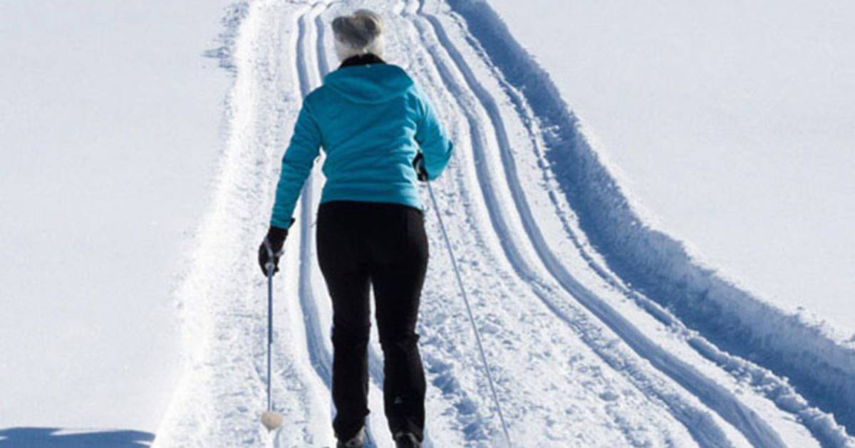 a woman cross country skiing down a trail