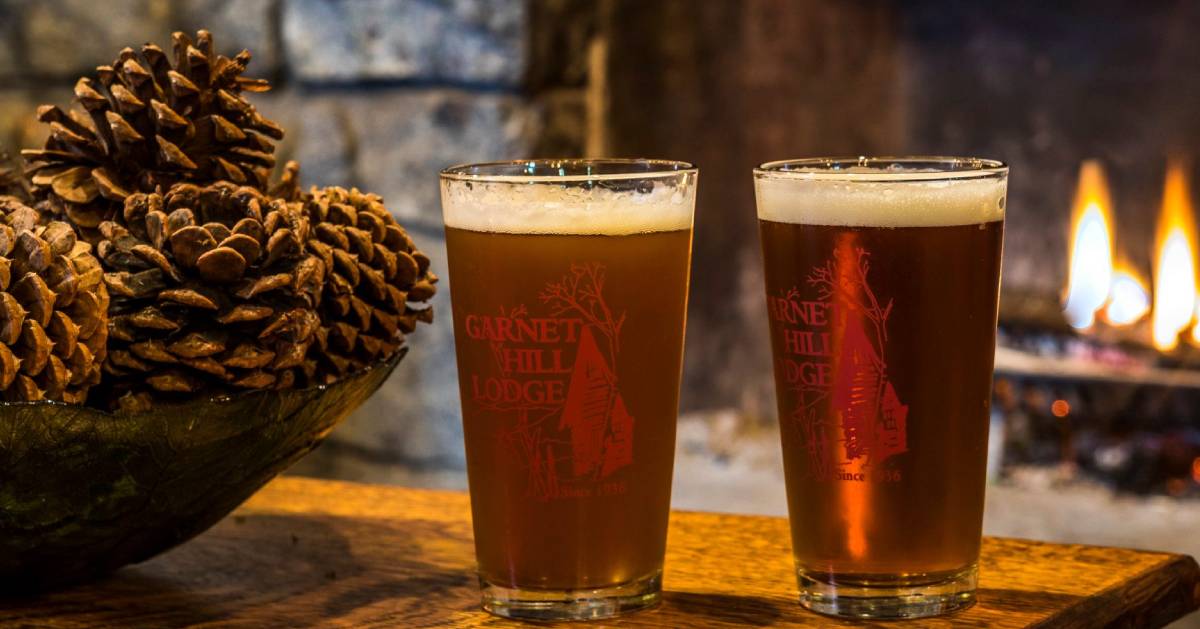 two beers in front of fire, there's pinecones