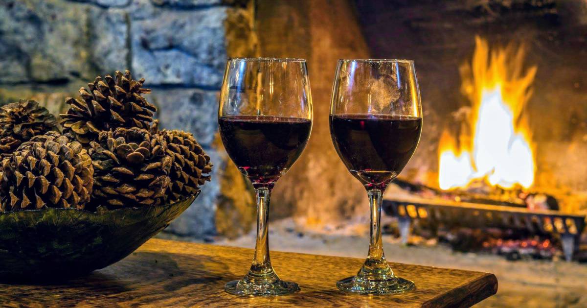 two glasses of wine by the fire