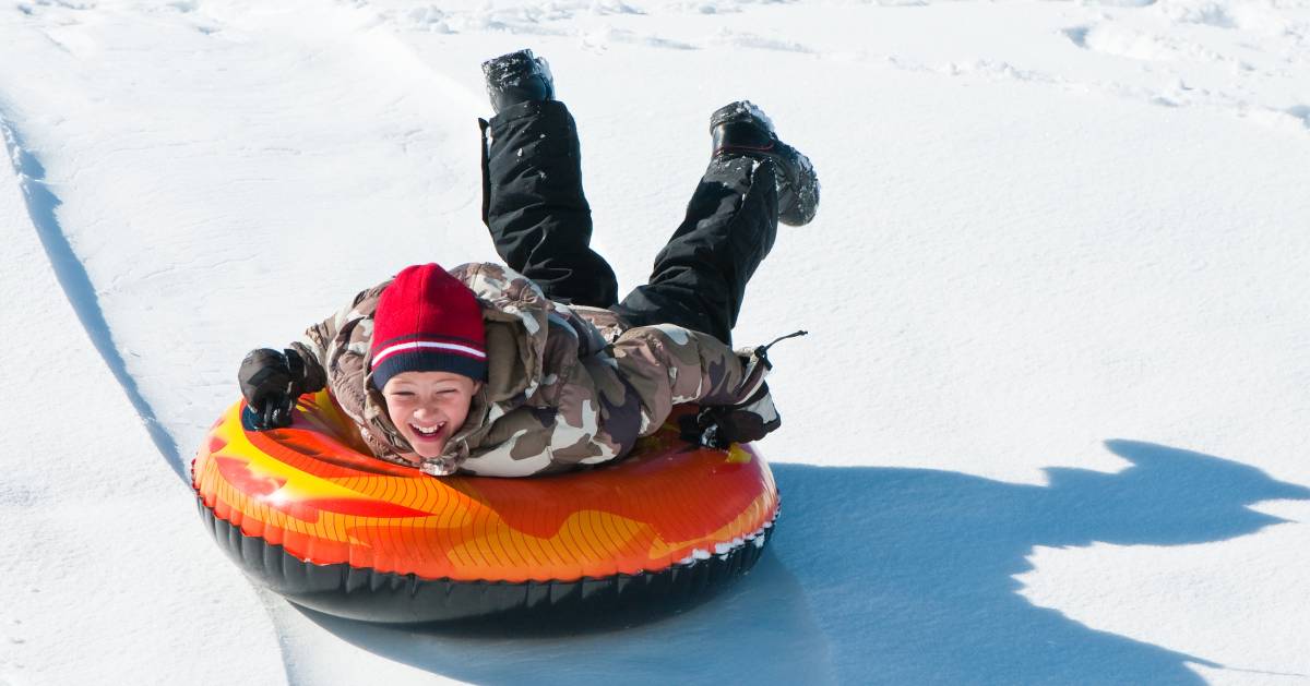 kid snow tubing down a hill