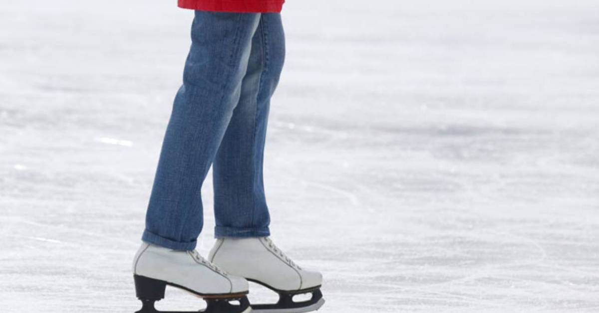 person wearing blue jeans and wearing white ice skates