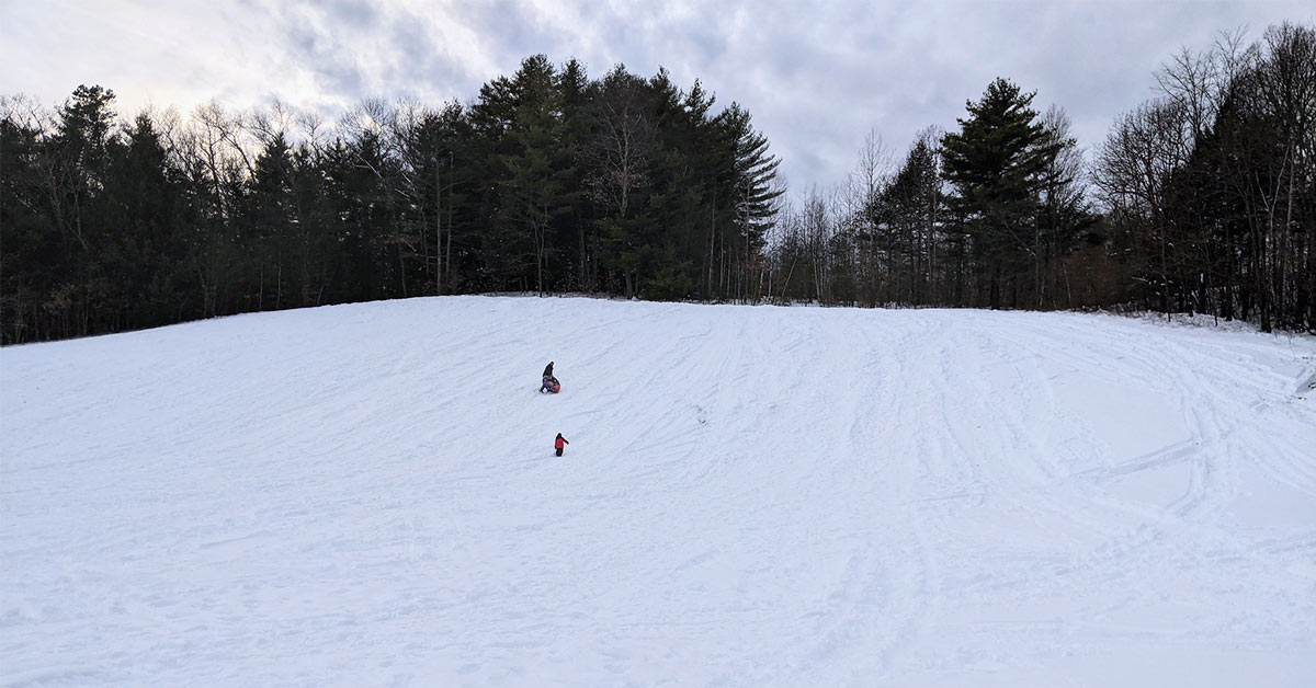 father and son climbing up the tubing hill at lake george recreation center