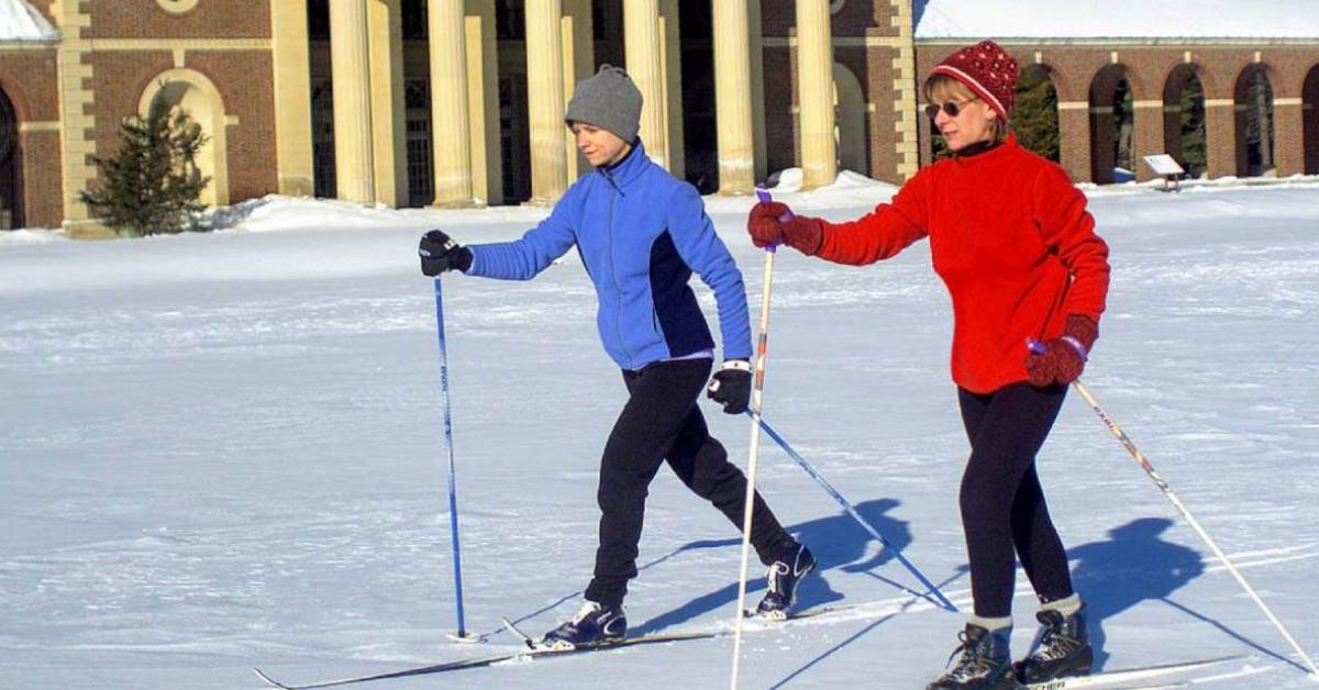 two cross country skiers, one with a red coat and the other with a light blue coat