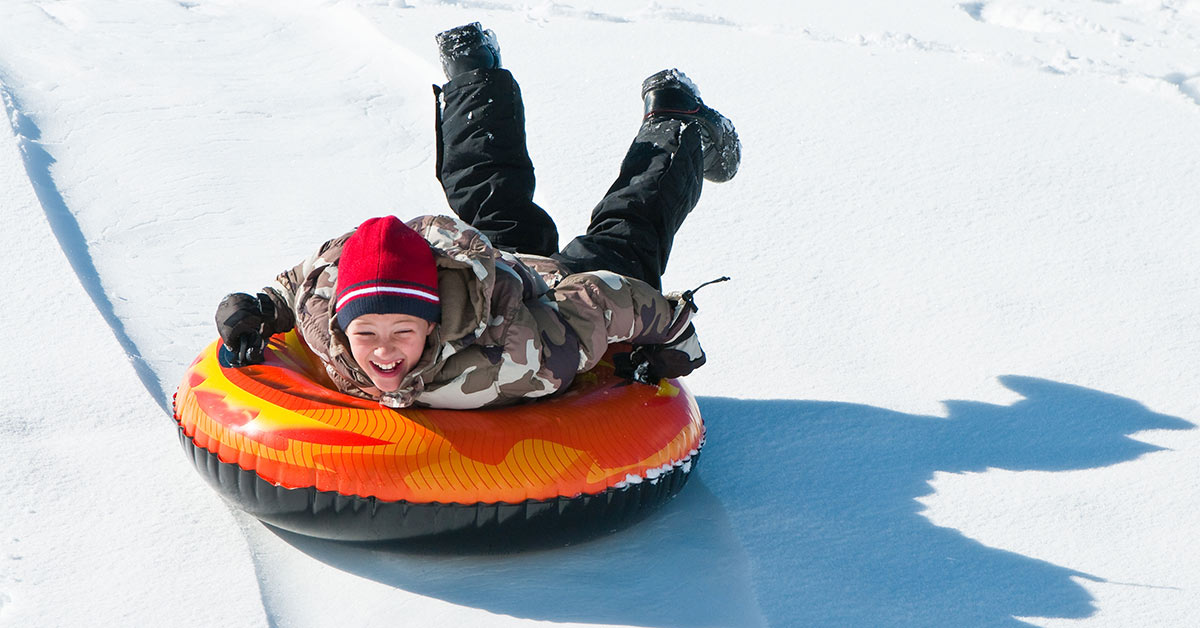 boy on an orange snow tube