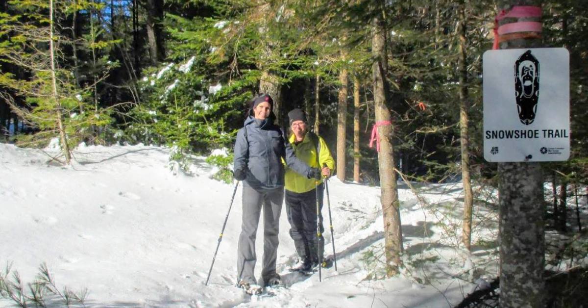 two women wearing snowshoes and smiling