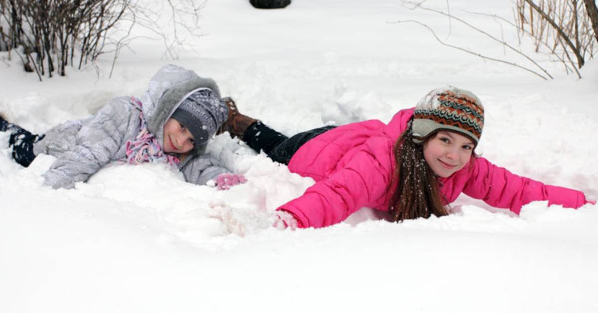 two kids laying in snow