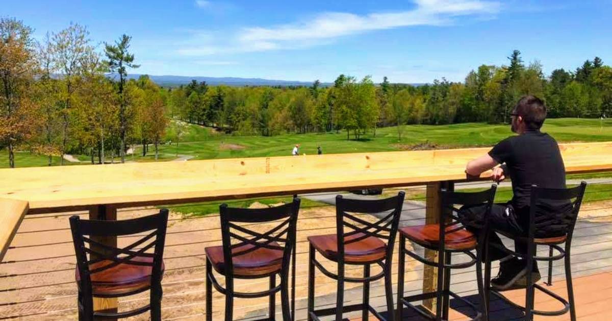 person on stool outdoors looking out at golf course