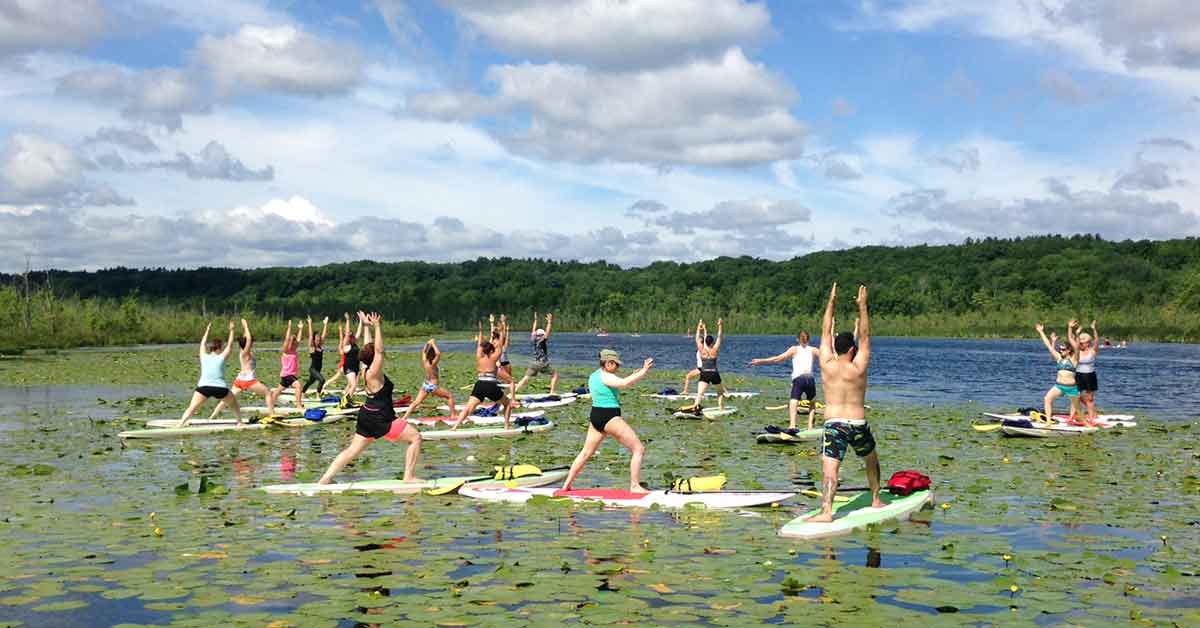 a group of people doing yoga on kayaks on a lake