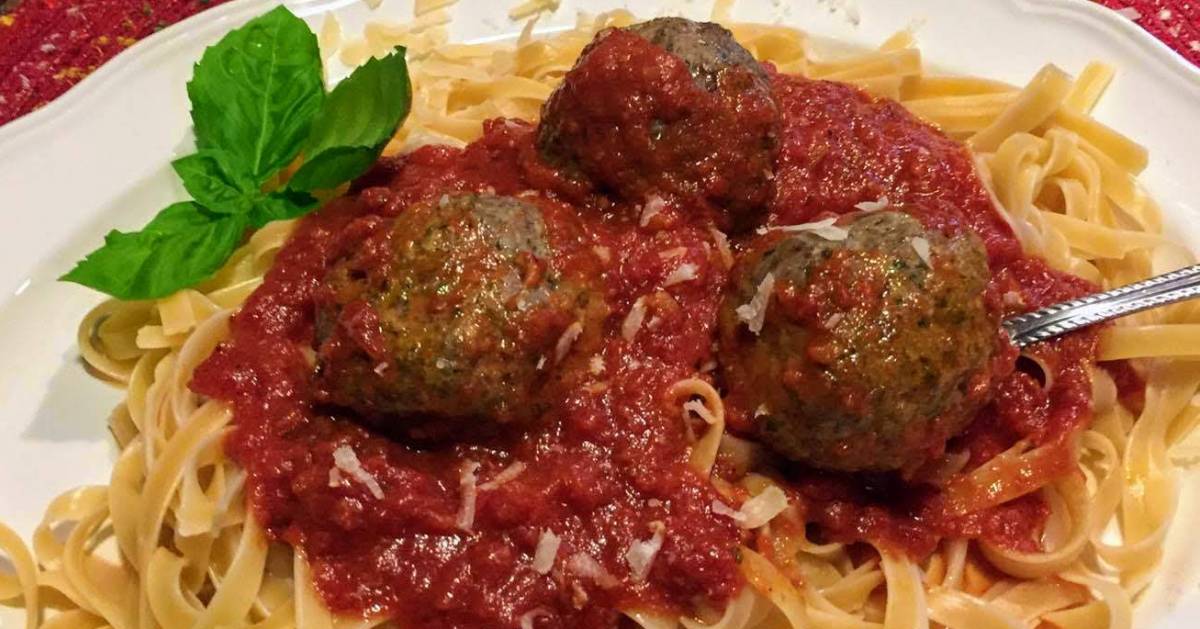 meatballs and pasta with sauce, garnished with basil