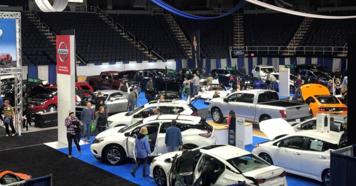 people walking around an indoor auto show