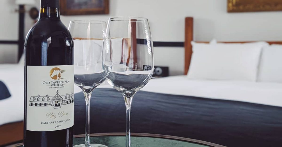 two wine glasses, a bottle of wine, and two beds in a room