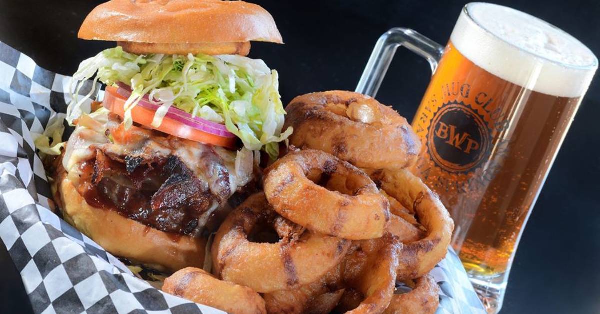 basket with a burger and onion rings, plus a mug of beer