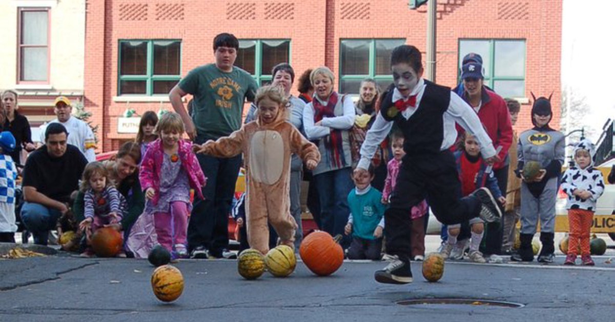 kids doing pumpkin bowling on street