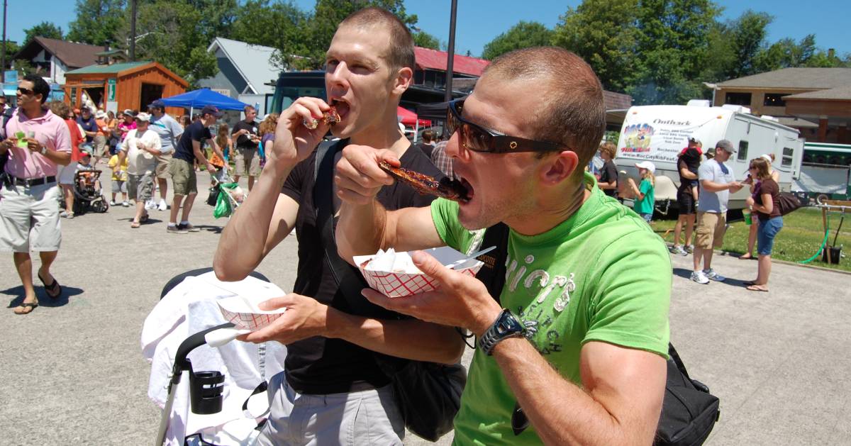 two guys eating barbecue fare at festival
