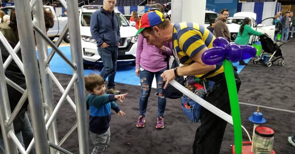 man making balloon animals at a show