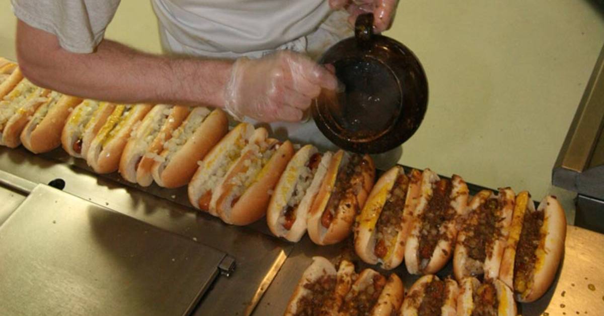 man making hot dogs on table