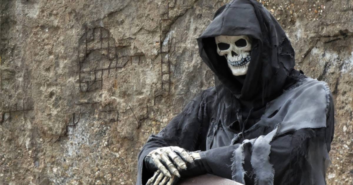 a skeleton in a grim reapers outfit, folding his hands together creepily