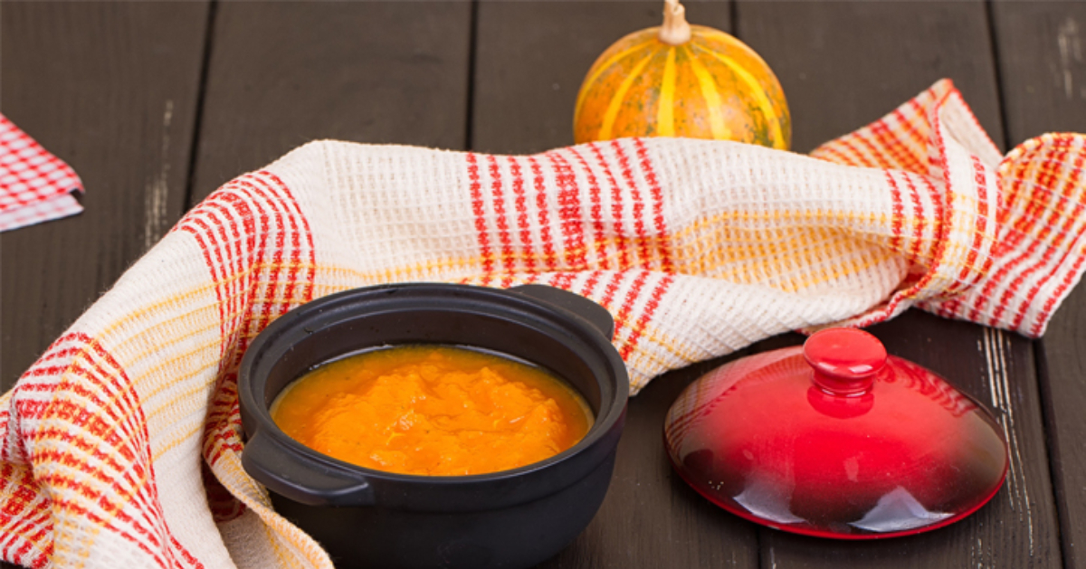 orange soup displayed with a nice blanket and a pumpkin