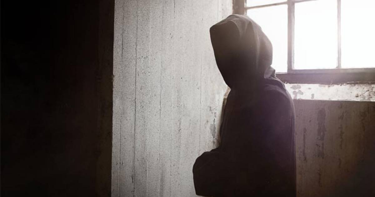 a hooded figure inside old wooden building