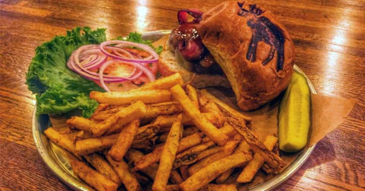 a plate with a burger and fries, the burger has an image of a moose on it