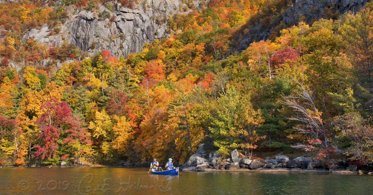 people in a boat on a lake in the fall