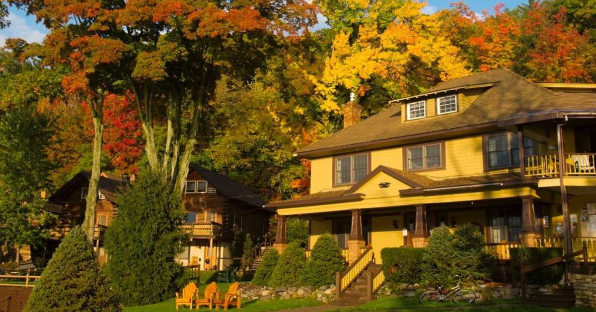 cottage and Adirondack chairs among fall foliage