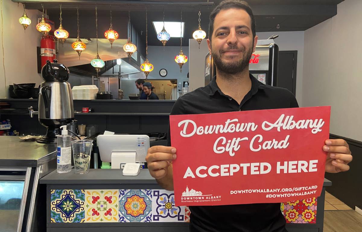 business owner holding downtown albany gift card sign