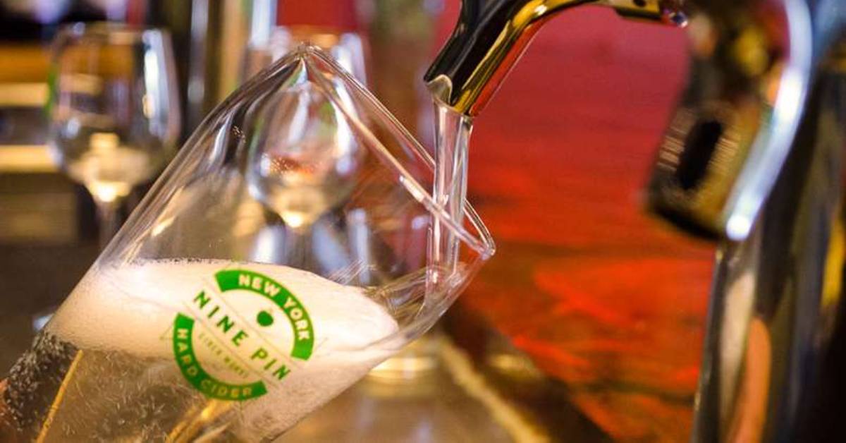 hard cider being poured into a glass from a tap