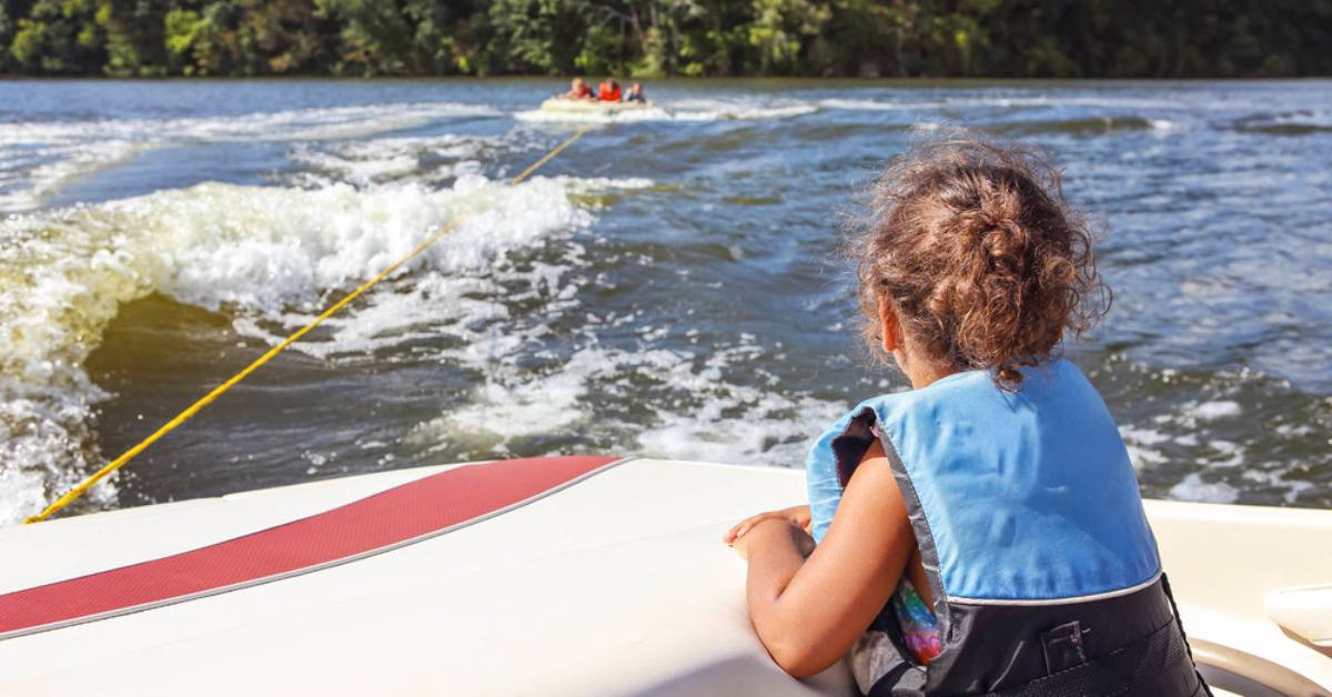 little girl on boat watching people tubing